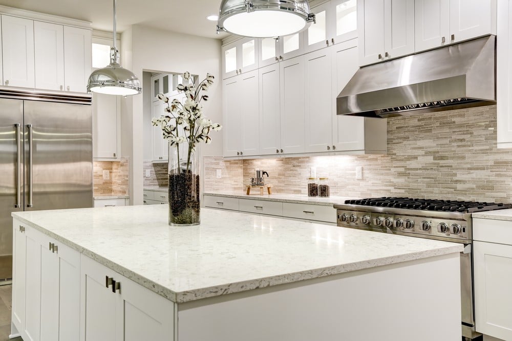 Gourmet-kitchen-features-white-shaker-cabinets-with-marble-countertops-stone-subway-tile-backsplash