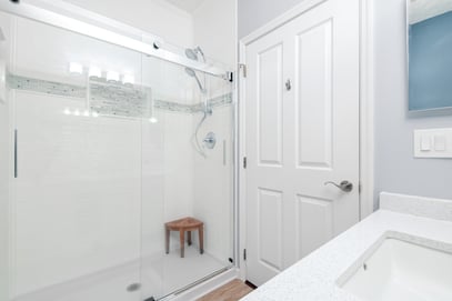 White textured Onyx shower walls with accent strip and large shower caddy