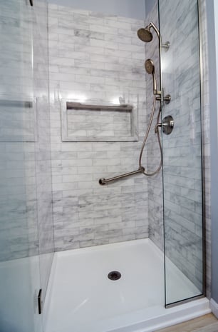 Grey-marbled Onyx shower walls with subway tile texture and oversized shower caddy